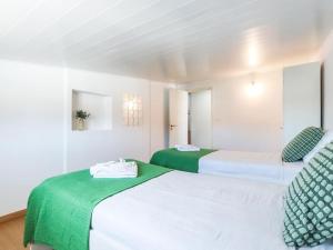 zwei Betten mit grüner und weißer Bettwäsche in einem Zimmer in der Unterkunft Vita Portucale ! Charneca Caparica Pool in Charneca