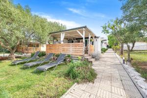a row of chairs sitting in the grass near a building at Mobile homes Bepo in Sveti Filip i Jakov