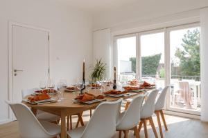 a dining room with a wooden table and white chairs at Pins Dorés - A Luxurious and beautifully decorated villa with terrace and parking near the beach in Knokke-Heist