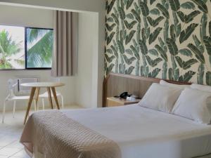 1 dormitorio con cama, mesa y pared en Ilha Porchat Hotel en São Vicente