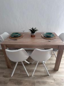 una mesa de madera con sillas blancas y una mesa con platos y vasos. en TORREJÓN, en Jerez de la Frontera
