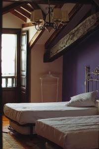 Hotel Palacio La Casona de Cerrazo في Cerrazo: سريرين في غرفة نوم مع جدران أرجوانية
