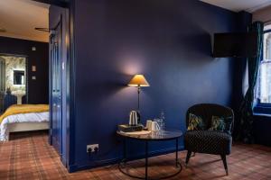 a room with a blue wall with a table and a bed at The Mash Tun in Aberlour