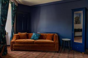 eine braune Couch in einem blauen Zimmer mit Spiegel in der Unterkunft The Mash Tun in Aberlour