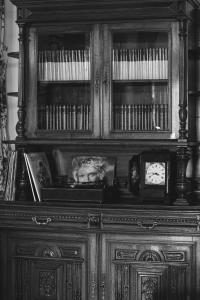 een houten kast met boeken en klokken erop bij Hotel Palacio La Casona de Cerrazo in Cerrazo