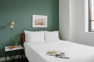 - une chambre avec un lit blanc et un livre dans l'établissement Sonder Le Guerin, à Montréal