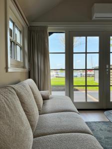 a living room with a couch in front of a window at HAVENZICHT HUISJE, chique ingericht, compleet uitgerust, prachtig uitzicht! in Belt-Schutsloot