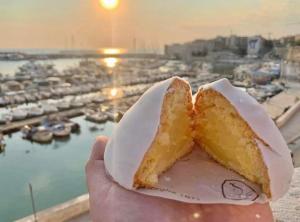 a person holding a piece of food in front of a harbor at ARCO in Bisceglie