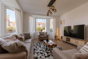 a living room with couches and a flat screen tv at Pins Dorés - A Luxurious and beautifully decorated villa with terrace and parking near the beach in Knokke-Heist