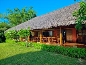 a house with a thatched roof and a yard at Miavaka Lodge in Ambatobe