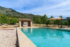 a swimming pool with an umbrella and a building at Agroturisme Subies in El Port de la Selva