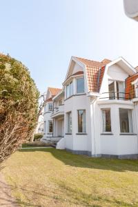 una gran casa blanca con un patio de césped en Pins Dorés - A Luxurious and beautifully decorated villa with terrace and parking near the beach en Knokke-Heist