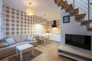 a living room with a couch and a flat screen tv at Piaskowe Domki in Grzybowo