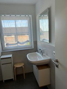 a bathroom with a sink and a window and a stool at Ferienwohnungen Christoph in Pfaffing
