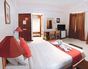 ein Schlafzimmer mit einem großen Bett mit rot-weißer Bettwäsche in der Unterkunft The Humbertos Hotel in Davao City