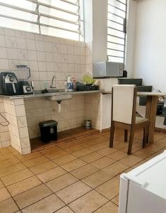 a kitchen with a sink and a table and a chair at Quarto Proença in Campinas