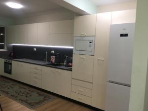 een keuken met witte kasten en een koelkast bij Апартамент 170 кв.м за 6-ма, село Ягодово, Пловдивско in Plovdiv