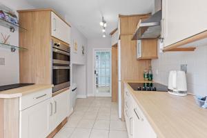 a kitchen with white cabinets and white appliances at Pebble Corner with Free Parking By My Getaways in Worthing