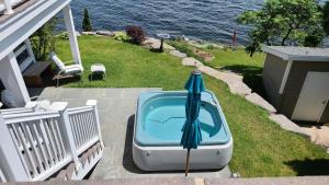 a bath tub with an umbrella sitting on the grass at Loza house adirondack screened-in porch unit lake front in Plattsburgh