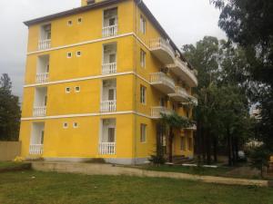 a yellow building with white balconies and trees at Ureki - Evkalipt in Ureki