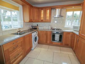 a kitchen with wooden cabinets and a sink and a dishwasher at 2 Carlton Cottage in Enniskillen