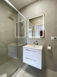 a bathroom with a white sink and a shower at Apartamenty Przemyśl BG in Przemyśl