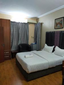 um quarto de hotel com uma cama grande e uma cadeira em A's Hospitality em Ikeja