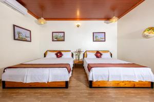 two beds in a room with white walls and wood floors at Trang An Family Homestay in Ninh Binh