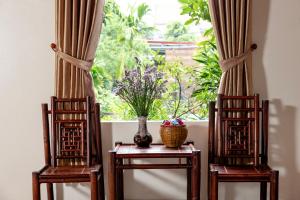 due sedie e un tavolo con un vaso e una finestra di Trang An Family Homestay a Ninh Binh Altre 19 foto