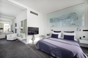 a white bedroom with a bed and a tv at Farol Hotel in Cascais