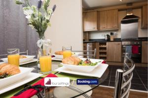 a dining room table with plates of food and orange juice at Luxury 6 Bedroom Contractor House By Your Lettings Short Lets & Serviced Accommodation Peterborough With Free WiFi in Peterborough
