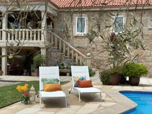 two chairs with pillows sitting in front of a house at Conde Dúplex - Casal do Conde in Caldas de Reis