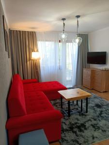 een woonkamer met een rode bank en een tafel bij Pokoje Gościnne U Broni in Mielno