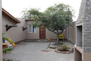 a courtyard with a tree in front of a house at Wild Eden Self-Catering Accommodation in Swakopmund