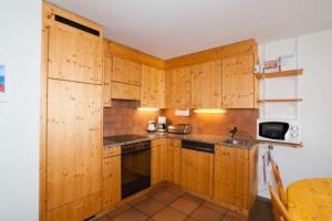 een keuken met houten kasten en een wastafel bij Unterkunft il balcun tort - b48496 in Pontresina