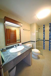 a bathroom with a sink and a toilet and a mirror at Jade Tower in Chiang Mai