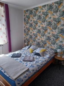 1 dormitorio con 1 cama y papel pintado con motivos florales en Apartament LORD en Toruń