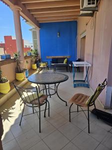 eine Terrasse mit Tischen und Stühlen und einer blauen Wand in der Unterkunft Appart Majorelle entier au Centre Ville in Kenitra