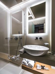 a bathroom with a tub, sink, and mirror at Golden Age Athens Hotel in Athens