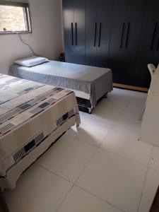Duas camas num quarto com piso em azulejo branco em Ampla e Aconchegante Casa no Bairro da Liberdade na Cidade de Campina Grande Pb em Campina Grande