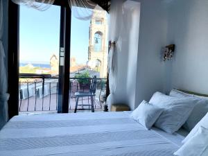 a bedroom with a bed and a balcony with a view at Vapori Otel in Bozcaada