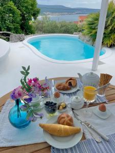 a table with breakfast food and a swimming pool at PAVI APARTMENTS Life Style House with private pool in Kornić