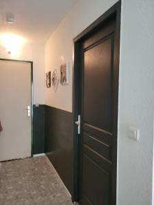 a hallway with a black door in a room at Studio en RDC à LAMALOU LES BAINS in Lamalou-les-Bains