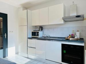 a kitchen with white cabinets and a microwave at Kuća za odmor Šimun in Vukovar
