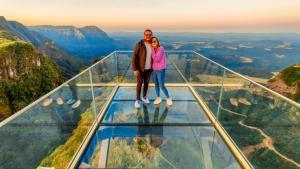 a man and a woman standing on top of a glass floor at Pousada Caminhos do Mel - Urubici - SC in Urubici
