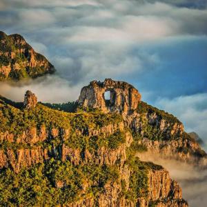 a mountain in the clouds with a hole in it at Pousada Caminhos do Mel - Urubici - SC in Urubici