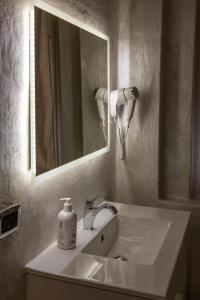een wastafel in de badkamer met een spiegel en een fles zeep bij Infinity Passion in Rho