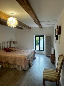een slaapkamer met een bed, een stoel en een kroonluchter bij La Maison de Melman in Quettreville-sur-Sienne