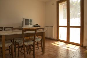 una sala da pranzo con tavolo, sedie e TV di Agriturismo Sant'Orsola a Follonica