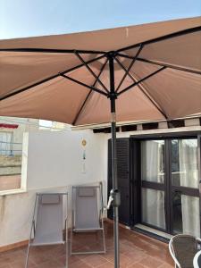 a large umbrella on a patio with two chairs at Appartamento Geco Rosso in Noto Marina